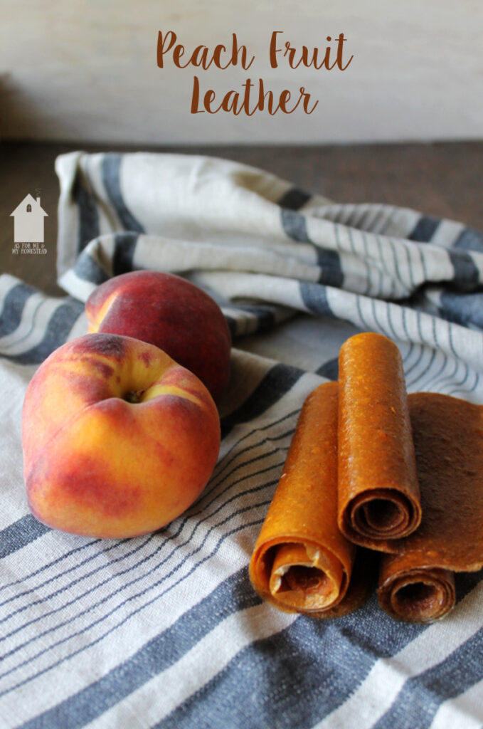 A striped linen table cloth with peaches and rolls of homemade peach fruit leather on top